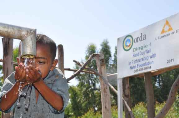 A child cools off with drinking water. Source: A Glimmer of Hope