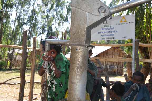 A young woman drinks from one of the wells. Source: A Glimmer of Hope