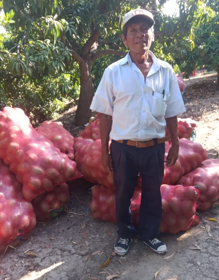 Agricultor delante de su cosecha. Fuente: Perucal